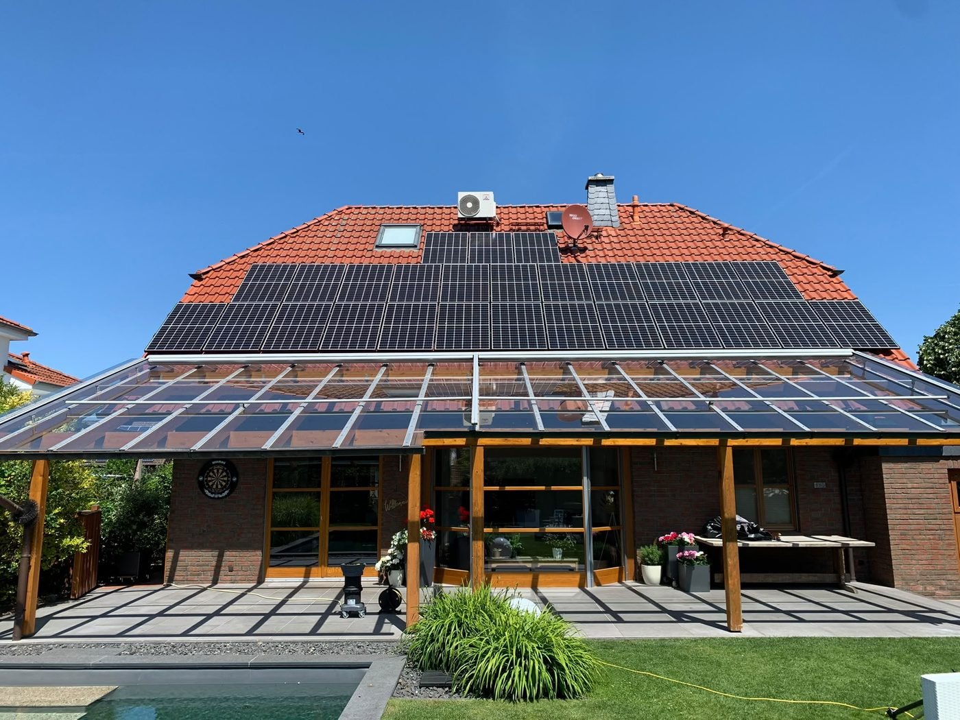 Einfamilienhaus mit sauberer Photovoltaikanlage über der Glas-Terrassenüberdachung