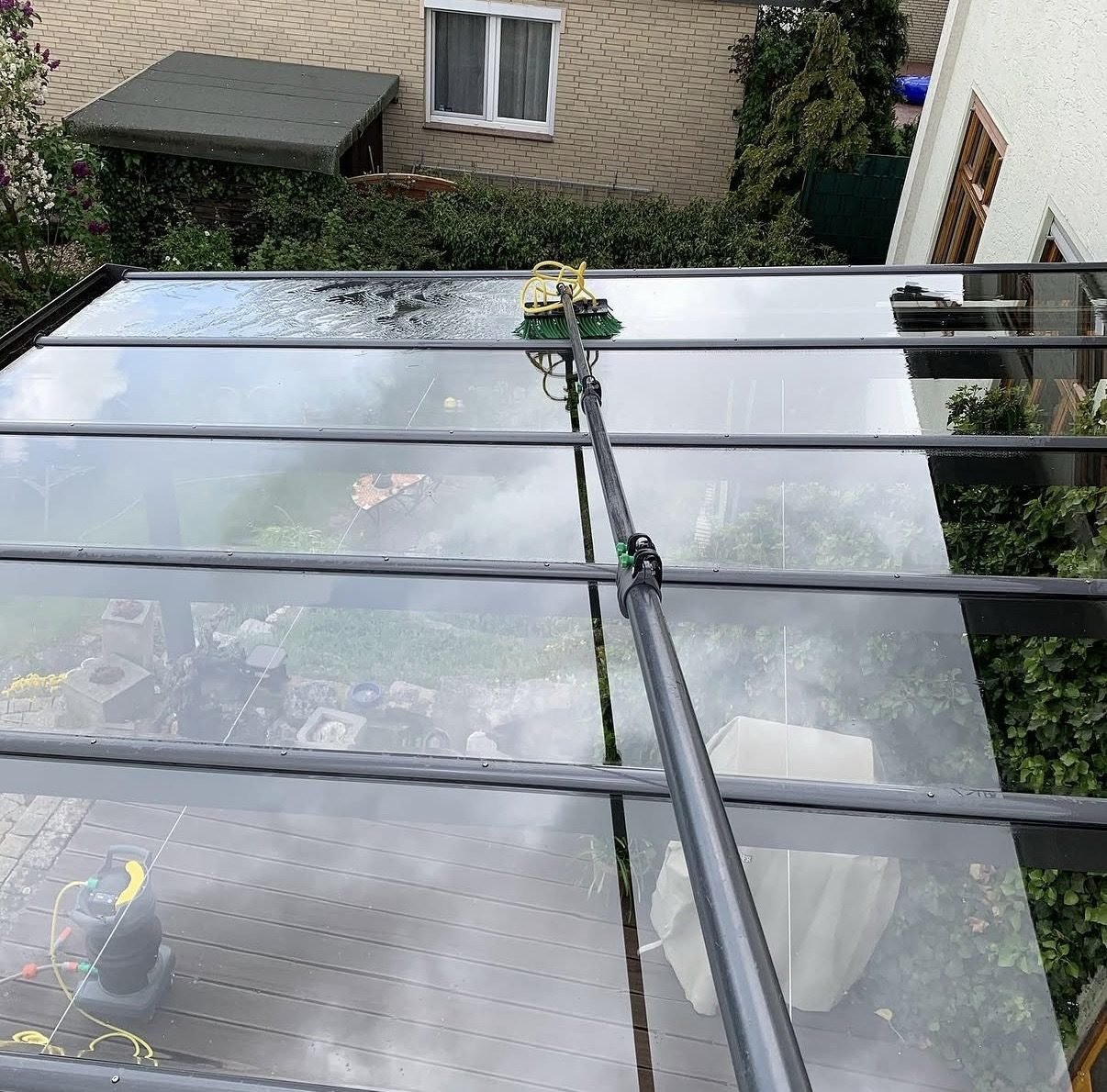 Glas-Terrassendach wird mit Reinwasser und Teleskopbürste gereinigt